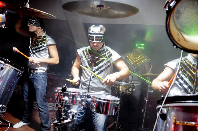 Барабанщики RhythmMen у світлодіодних костюмах збоку сцени